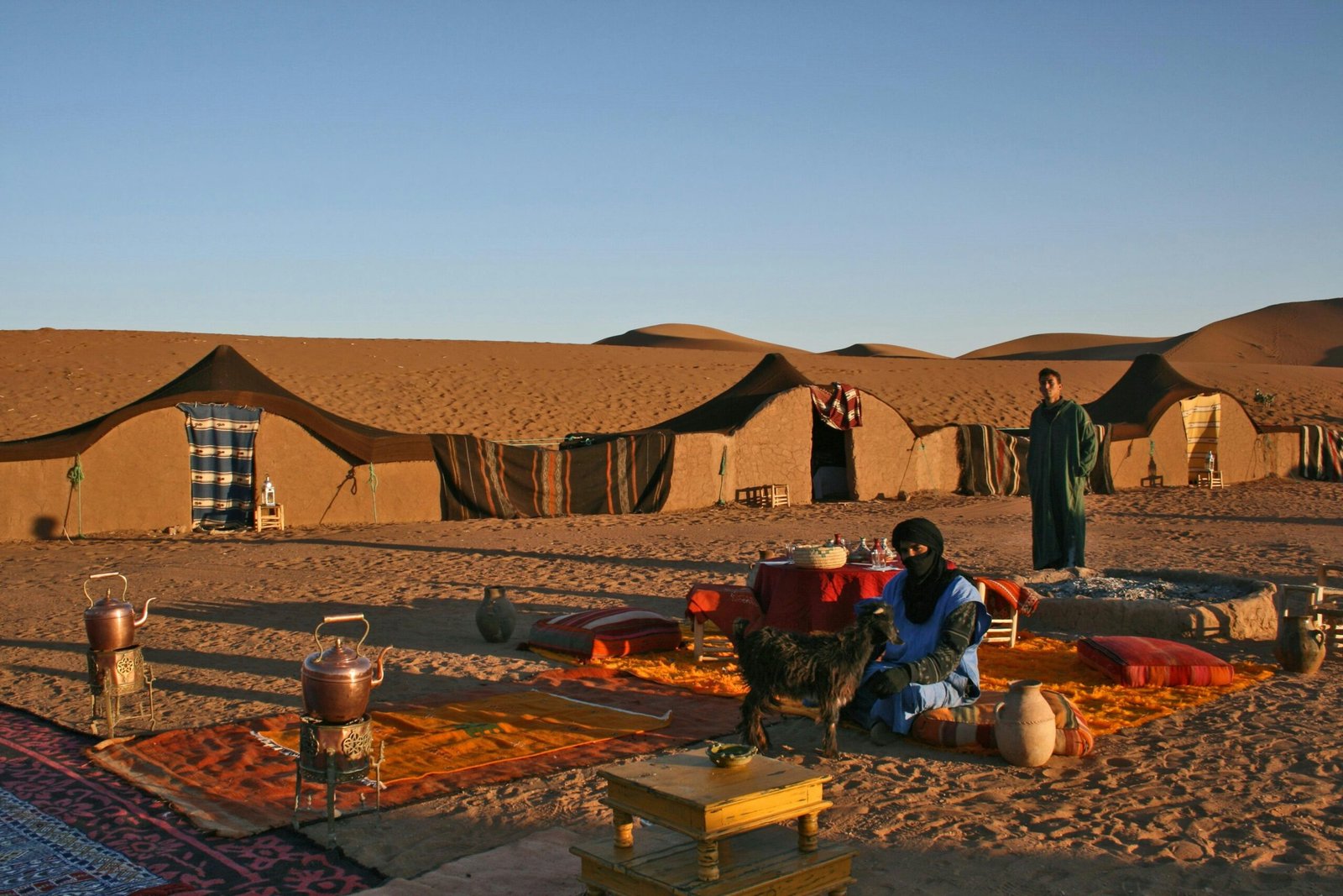 IEnjoy a magnificent seating area in a luxurious Sahara Desert Glamping camp, where warm colors harmonize with the stunning nature in the heart of the morocco road trip