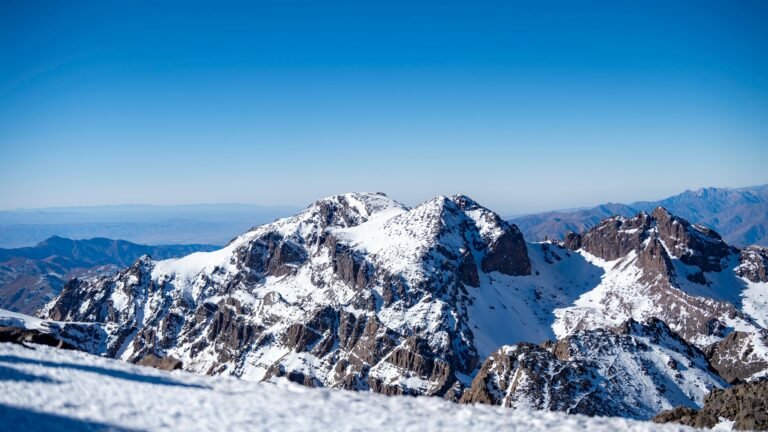 A breathtaking winter landscape of Mount Toubkal,the highest peak in North Africa, dusted with pristine snow under a clear blue sky.