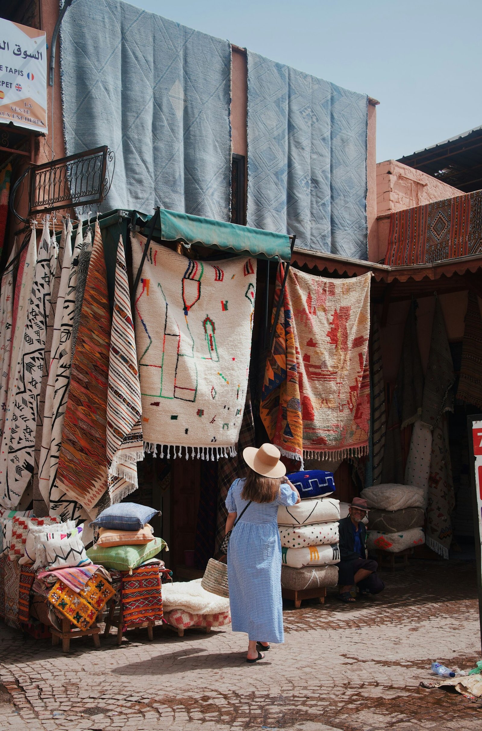 A tourist gazes with curiosity at the intricate colors of a Berber rug, where fingertips meet the authenticity of the weave. This moment captures the vibrant beauty of Berber culture Morocco, alive within the threads.