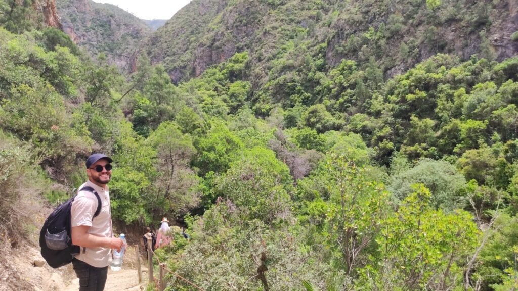 Hiking on the dusty trail towards the Grand Cascade of Akchour, with the Rif Mountains in the background. I am mid-way through the rewarding Akchour waterfalls hike, eager to discover the stunning natural beauty.
